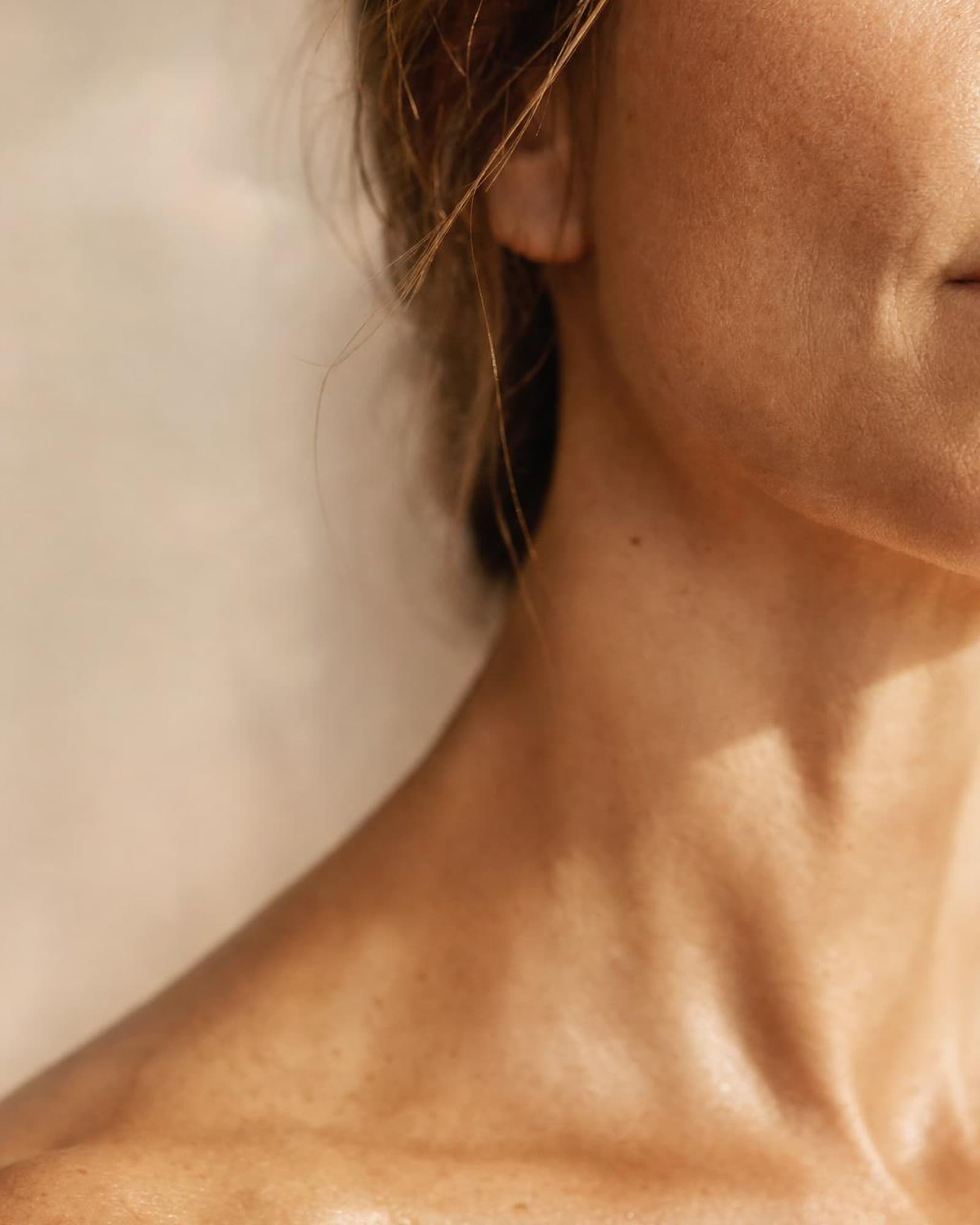 Warm light raking across a cheekbone — natural skin, considered care.